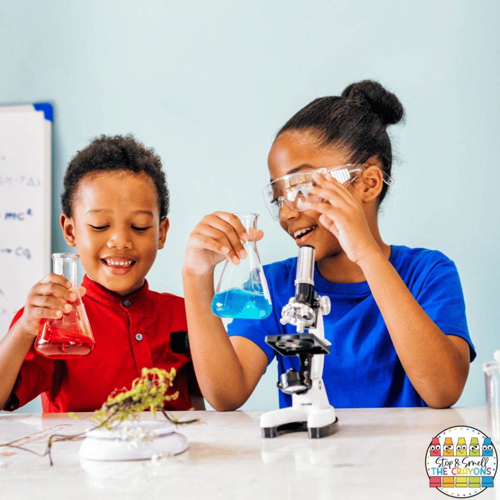 In this photo, two primary students are conducting a water science experiment using science exploration tools like beakers, microscopes and safety glasses.